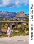 Woman exploring scenic mountain bridge under clear blue sky.