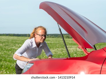 woman expresses bewilderment when she looks under hood of car
