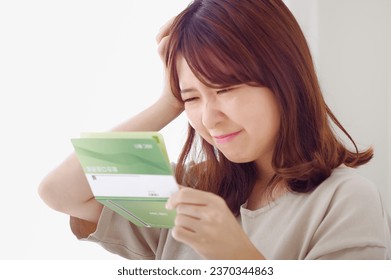 A woman with an expression that doesn't float while looking at her savings passbook