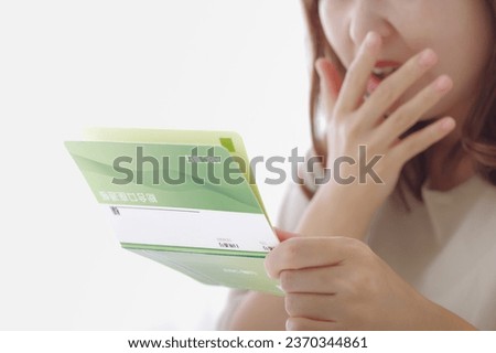 A woman with an expression that doesn't float while looking at her savings passbook