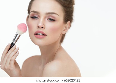 Woman Face Beauty. Closeup Of Sexy Girl Putting Blush With Facial Brush On White Background. Portrait Of Beautiful Young Woman Applying Makeup On Soft Healthy Skin. Cosmetic Concept. High Resolution