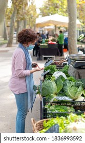 Woman With Face Mask Buying Vegetables At An Outdoor Market. New Normal Concept