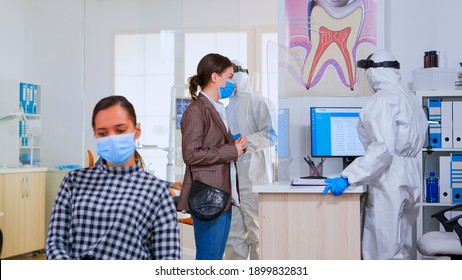 Woman With Face Mask Coming In Dental Clinic To Check Teeth Health During Coronavirus Pandemic. Concept Of New Normal Dentist Visit In Covid-19 Outbreak Wearing Protective Suit And Face Shield