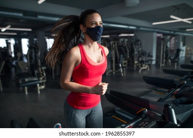 Woman With Face Mask Doing Exercise On Treadmill In Gym, Coronavirus Concept.