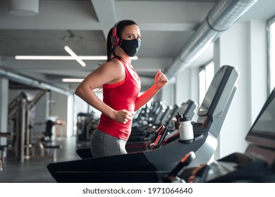 Woman With Face Mask Doing Exercise On Treadmill In Gym, Coronavirus Concept.