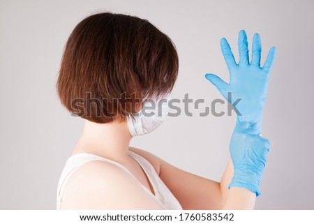 Woman with face mask and nitrile gloves on grey background, outbreak of coronavirus disease 2019 or covid-19