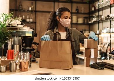 Woman With Face Mask Standing At The Counter, Shop Open After Lockdown, Packing Bag To Go