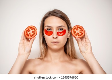 Woman Face Mask. Young Beautiful Female In Spa With Eye Patches, Holding Tomato On Face. Beauty Facial Mask, Skin Care And Treatment Concept