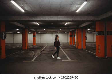 Woman With Facial Mask Walking In Empty Parking Garage With Neon Lights