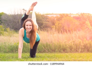 Woman Facing Camera In Bird Dog Yoga Pose Leg Lift Raise Outdoors In Nature Sunset Or Sunrise, Overexposed For Spiritual Light Effect Active Lifestyle Health Wellness Exercise Concept, Horizontal Shot