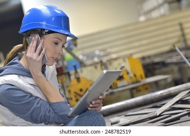 Woman in factory talking on mobile phone - Powered by Shutterstock