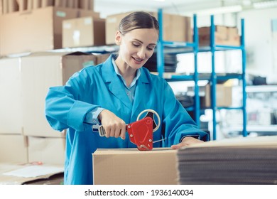 Woman In Factory Warehouse Packaging Goods For Shipment