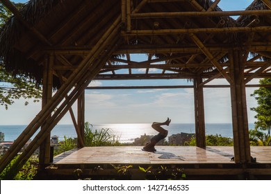 Woman Failing To Do A Headstand With Sunset Background. Yoga Retreat With Bamboo Hut And Red, Orange Sky. Handstand Balance. Shot In Montanita Beach, Ecuador. Funny.