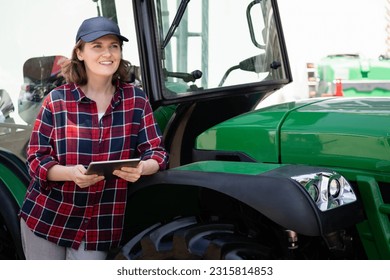 Woman farmer with a digital tablet and green agricultural tractor - Powered by Shutterstock