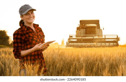 Woman farmer with digital tablet on a background of harvester. Smart farming concept. - Powered by Shutterstock