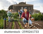woman farmer with a garden tool near growing seeds. Planting seeds and fertilizing the land on the farm. A farmer and his family grow organic berries and vegetables