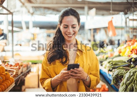 Woman at the farmer's market shopping, sending a text message on her smart phone. Young cheerful woman at the market. Smiling girl decided to cook a delicious and healthy meal ストックフォト © 
