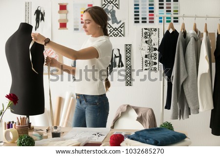 Woman fashion designer measuring mannequin, seamstress holding tape working with dummy in cozy creative design studio or tailor shop, dressmaking and sewing concept, exclusive unique clothes creation