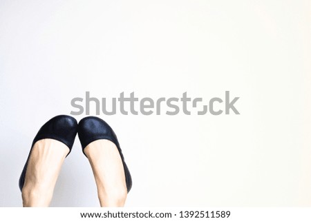 Woman fashion flat shoes black colour with lady feet waring step in the air isolated white wall soft background with copy space for text, and make it more bright to look artistic and different.