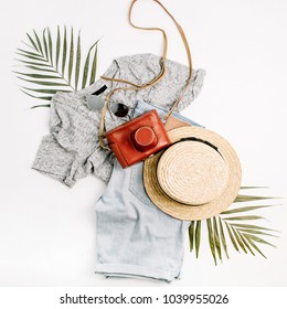 Woman fashion travel flatlay. Retro camera, straw, shorts, sunglasses and tropical palm leaf. Top view, flat lay.