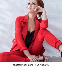 Woman In Fashionable Red Pantsuit In Studio