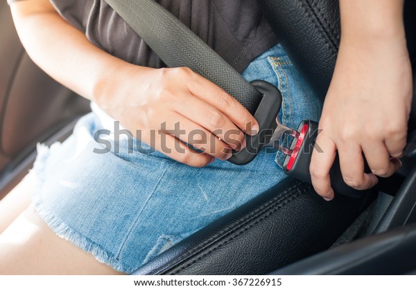 Woman fastening car\
seat belt before drive.