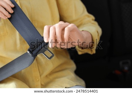 Woman fastening seat belt in car, closeup
