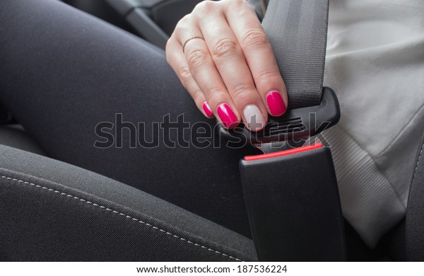 Woman fastening seat belt in\
car