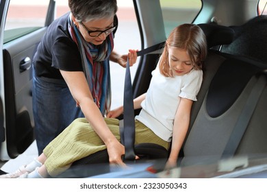 A woman fastens a child seated in a child seat in a car with a seat belt. Safety while driving. - Powered by Shutterstock