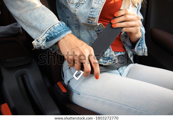 The woman fastens the seat belt in the car. Traffic\
Laws. Safety in the car