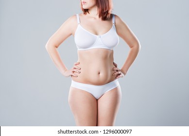 Woman with fat abdomen, overweight female body on gray background, studio shot