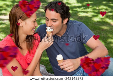 Woman feeding her friend ice cream against hearts