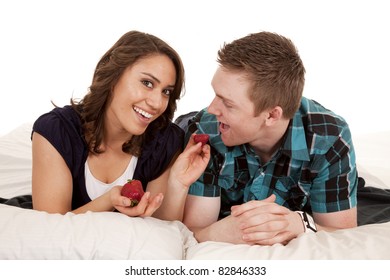 A Woman Feeding Her Man A Strawberry In Bed.