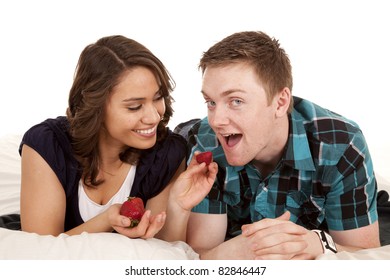 A Woman Feeding Her Man A Strawberry In Bed.