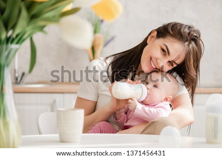 Woman feeding newborn with formula in a bottle.