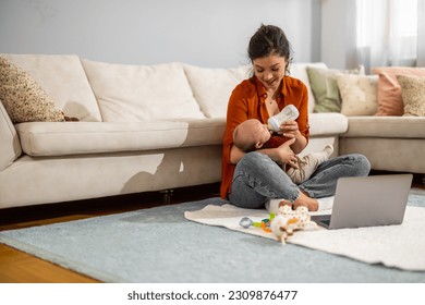 Woman feeding newborn with milk in a bottle.Beautiful mom feeds baby with formula while sitting on floor at home. - Powered by Shutterstock