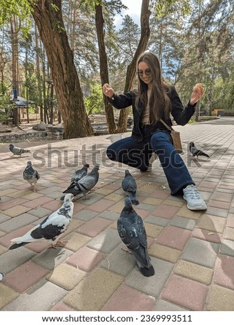 woman feeding pigeons in the park.girl in the park feeding pigeons.many birds.human kindness.love and care for animals.ornithology.bird lover. happy woman with pets.animals and birds in the city.