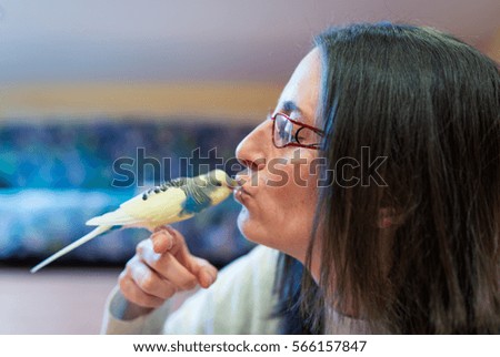 Woman feeding yellow budgerigar