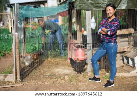 Woman feeds hens in chicken coop in the backyard of country house