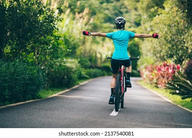 Woman feel free cycling on tropical park trail in summer - Shutterstock ID 2137540081