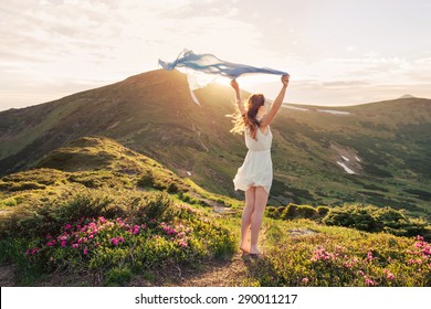 Woman feel freedom and enjoying the nature in the mountains with blue tissue in hands on sunset - Powered by Shutterstock