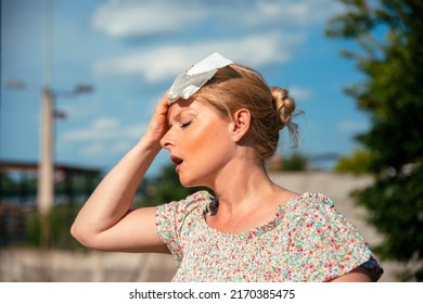 Woman feeling bad pain, heat, woman with heatstroke. Having sunstroke at summer hot weather. Mature Female under sunshine suffering from Headache. Person holds paper tissue on head - Shutterstock ID 2170385475