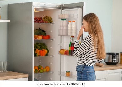 Woman Feeling Bad Smell From Fridge In Kitchen