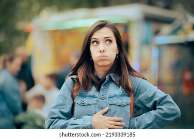 
Woman Feeling Hungry Looking for Something to Eat in Amusement Park. Person accusing stomachaches after eating street food at funfair festival
