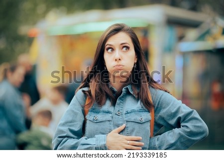 
Woman Feeling Hungry Looking for Something to Eat in Amusement Park. Person accusing stomachaches after eating street food at funfair festival
