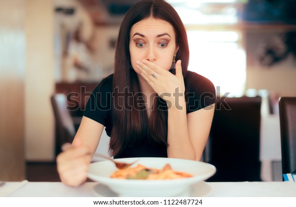 Woman Feeling Sick\
While Eating Bad Food in a Restaurant. Dinner customer having a bad\
experience feeling sick\
