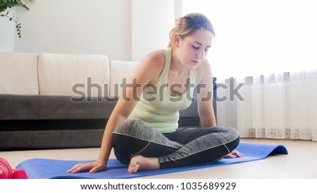 Woman feeling tired after exercising on fitness mat at living room
