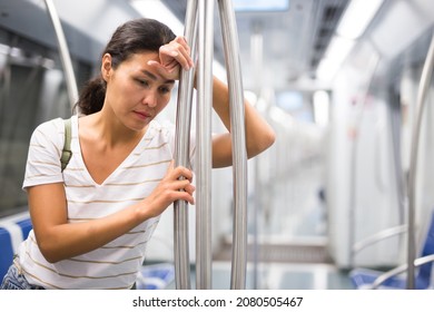  woman feeling tired while standing in metropolitan train and waiting for her stop.