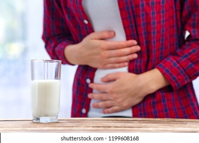 A woman feels bad, has an upset stomach, bloating due to lactose intolerance. Dairy intolerant person. Health care concept. Lactose intolerance and dairy products