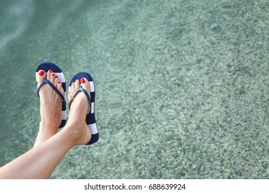 Woman Feet With Blue Flip Flops And Sea